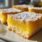 Close-up of perfect lemon bars dusted with powdered sugar, showcasing their bright citrus flavor.