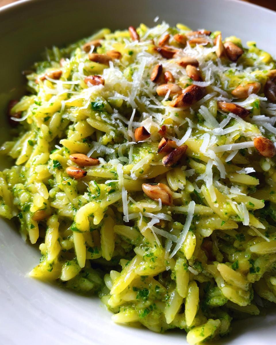 Close-up of Pesto Orzo pasta, topped with grated Parmesan cheese and toasted pine nuts.