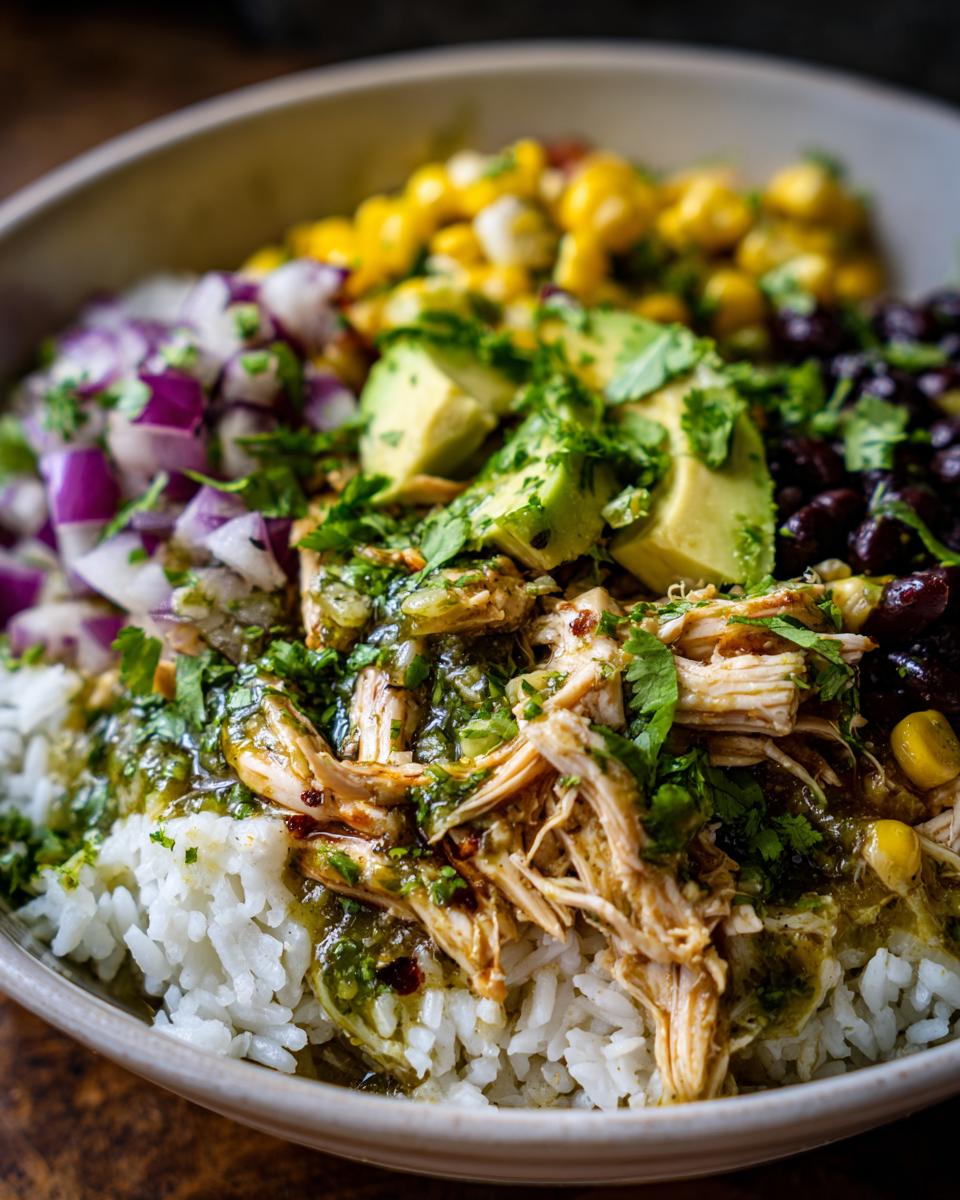 A delicious bowl of slow cooker salsa verde chicken taco bowl with rice, beans, corn, avocado, and red onion.