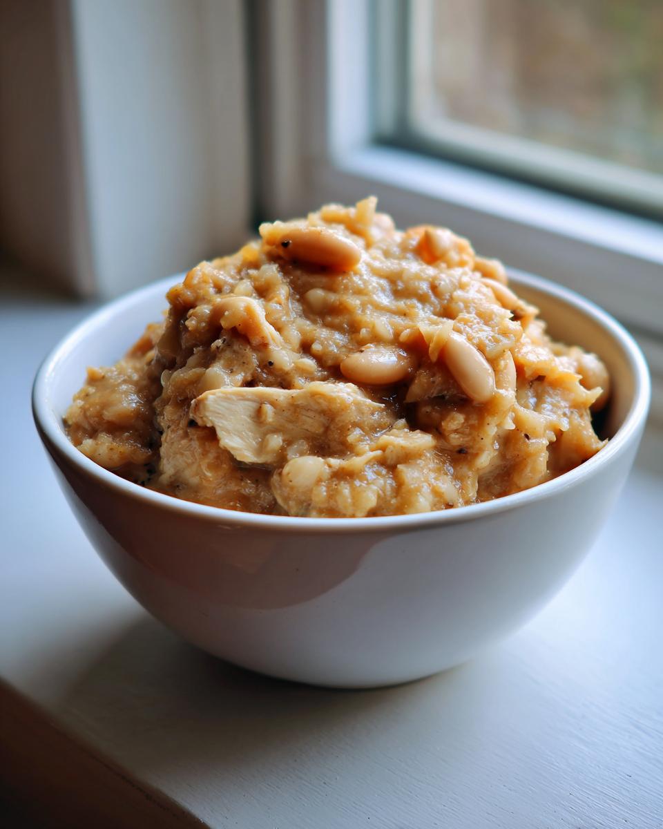 A white bowl filled with hearty Slow Cooker White Chicken Chili, featuring shredded chicken and white beans.